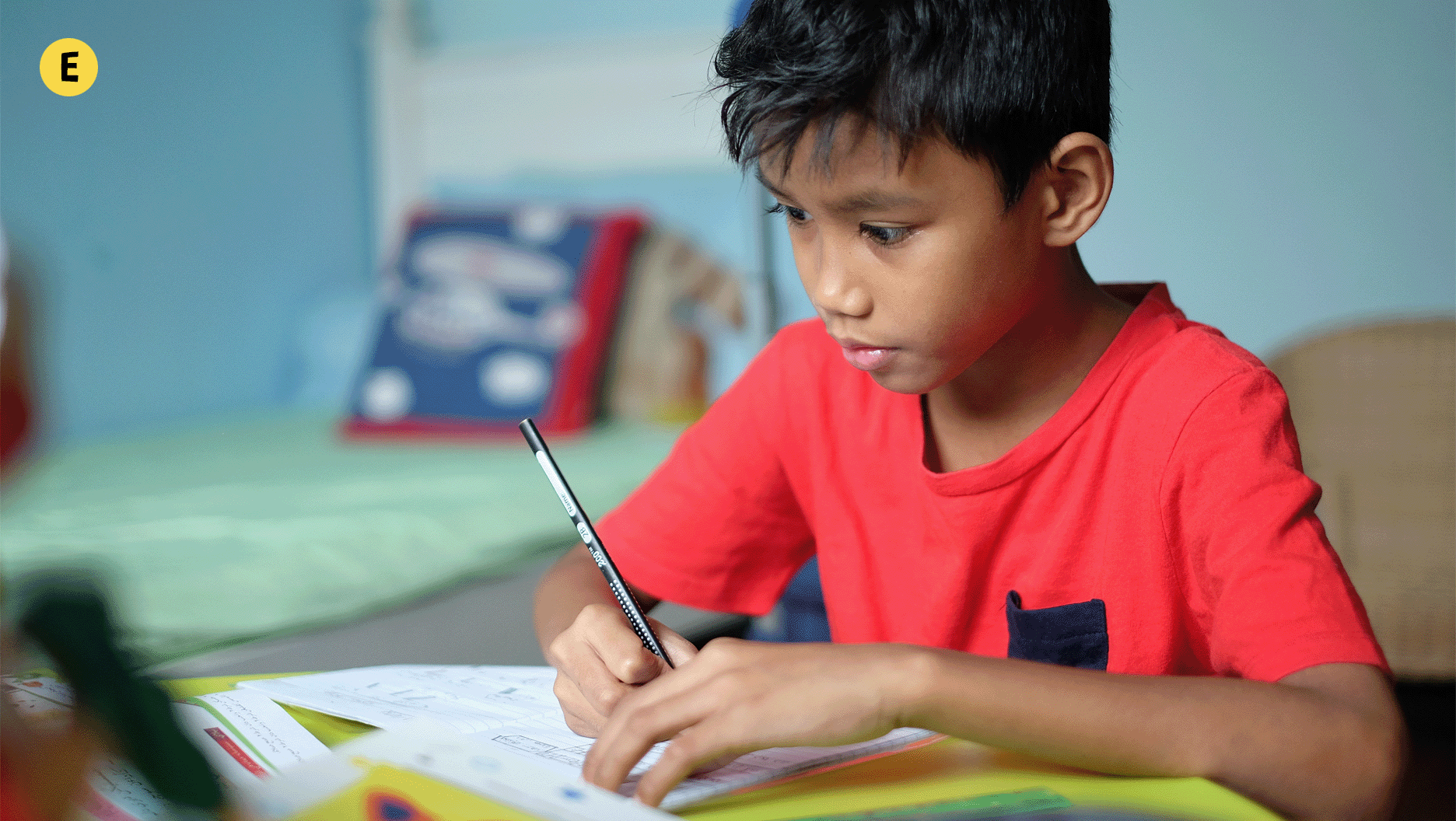 Un garçon fait ses devoirs à la maison.