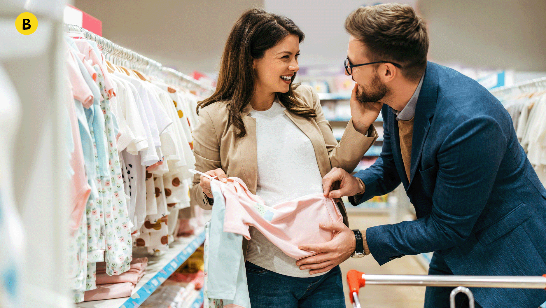 B. Une femme enceinte et un homme magasinent des vêtements pour bébé.