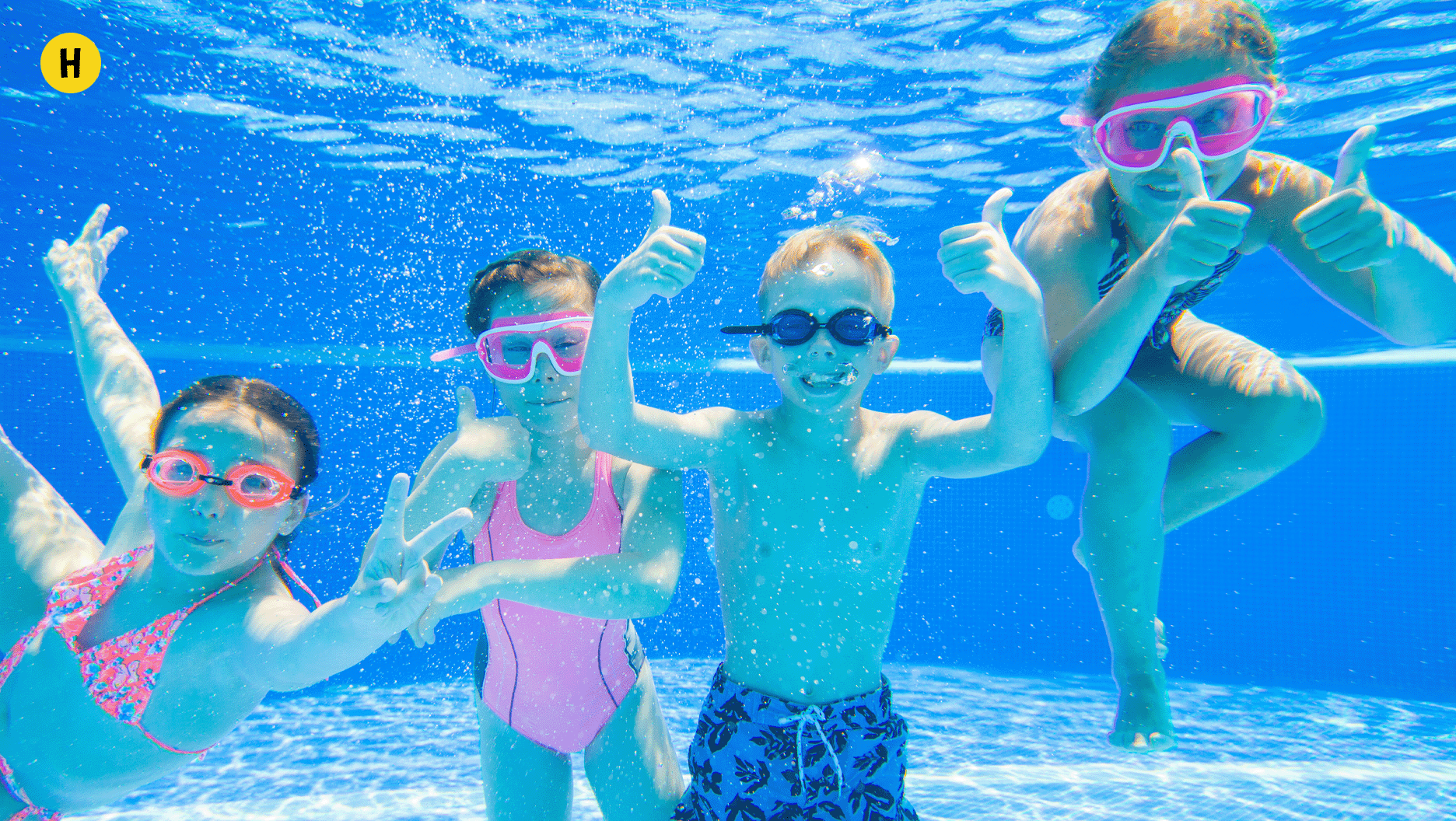H. Des jeunes jouent dans la piscine, sous l’eau.