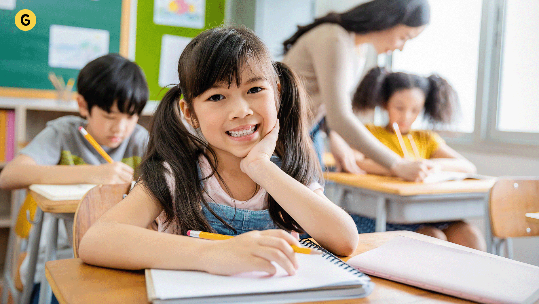 Une jeune fille est assise en classe et sourit.