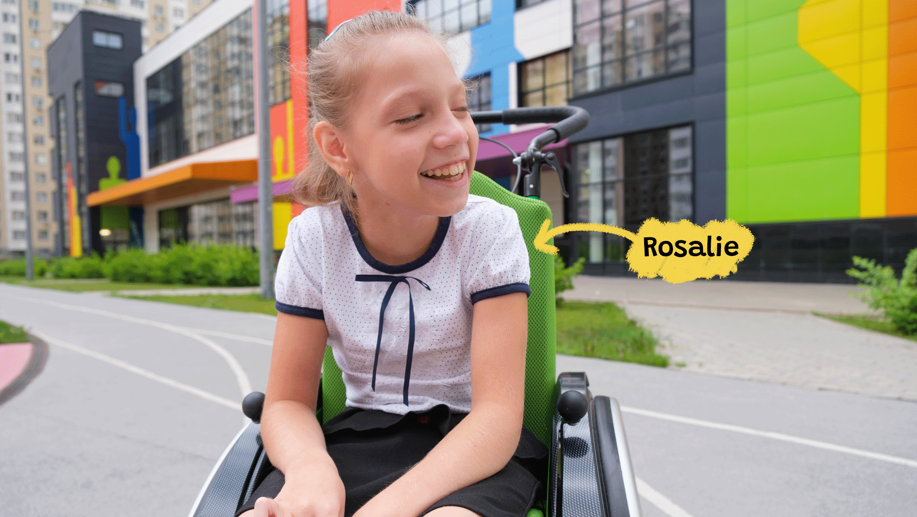 Une photo de Rosalie dans la cour d’école. Rosalie se déplace en fauteuil roulant.