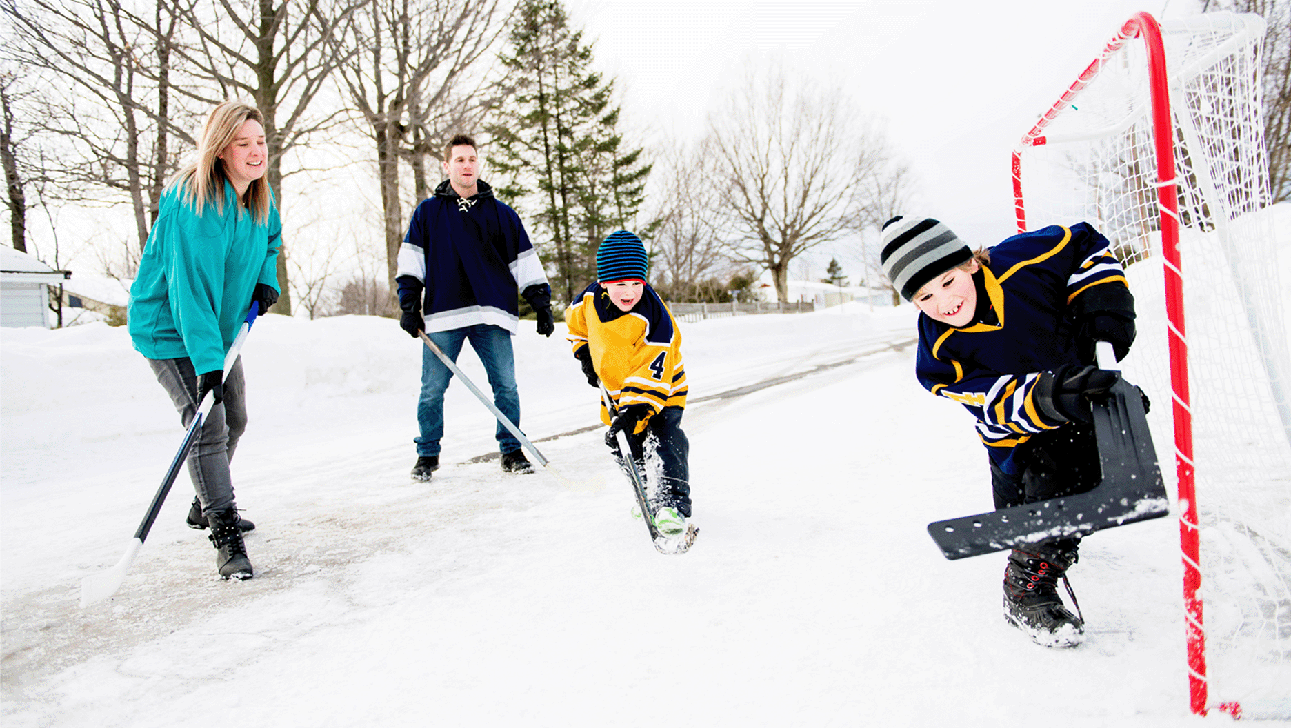 Une famille joue au hockey-balle dans la rue en hiver.