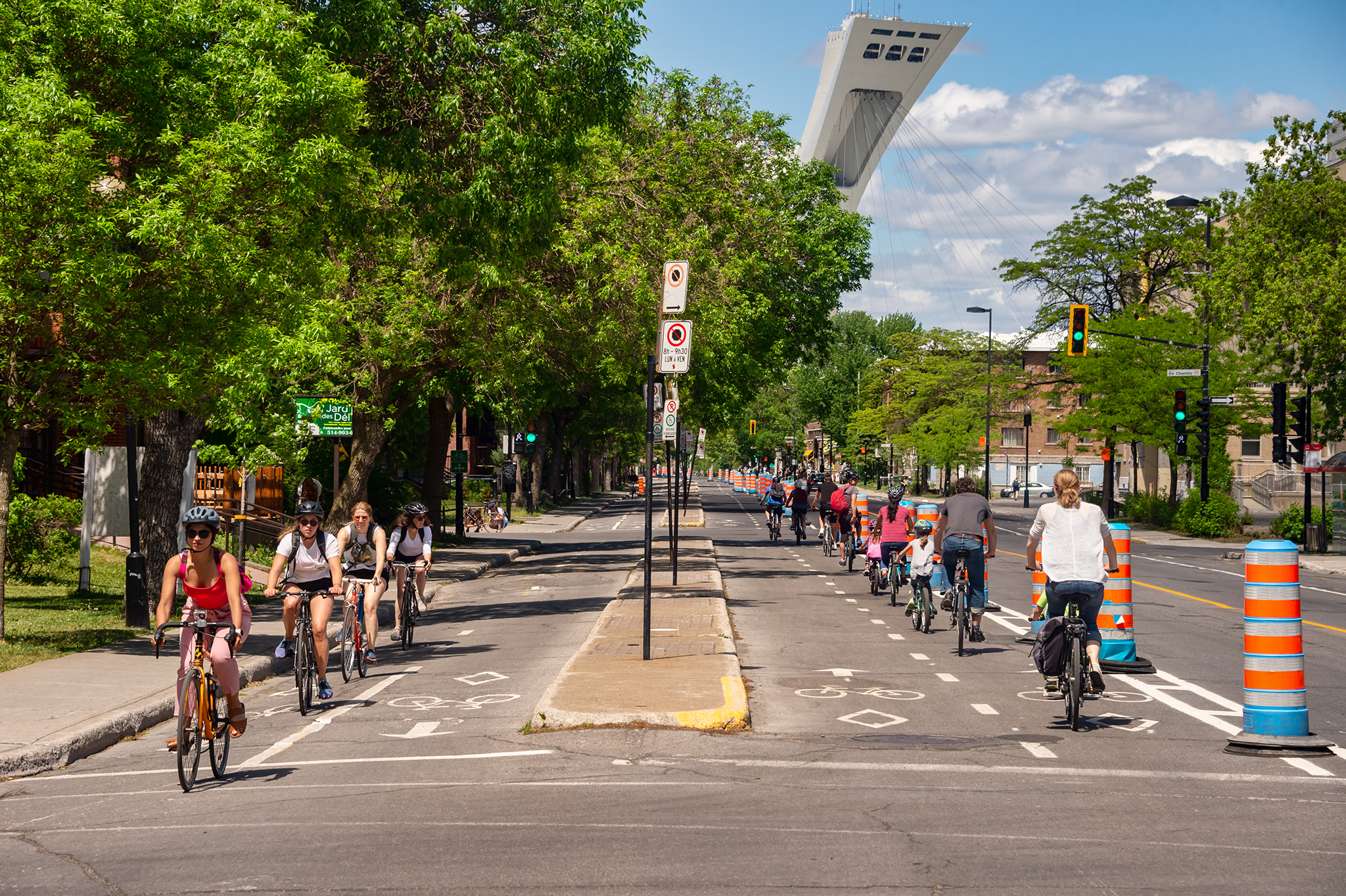 La photo montre des cyclistes circulant sur deux pistes cyclables allant en sens inverses. Les cyclistes empruntent chacune des pistes cyclables selon le sens qui est indiqué par des marques au sol, telles que des flèches et des dessins de vélos, peintes sur l’asphalte pour leur indiquer dans quel sens circuler sur chacune des pistes.